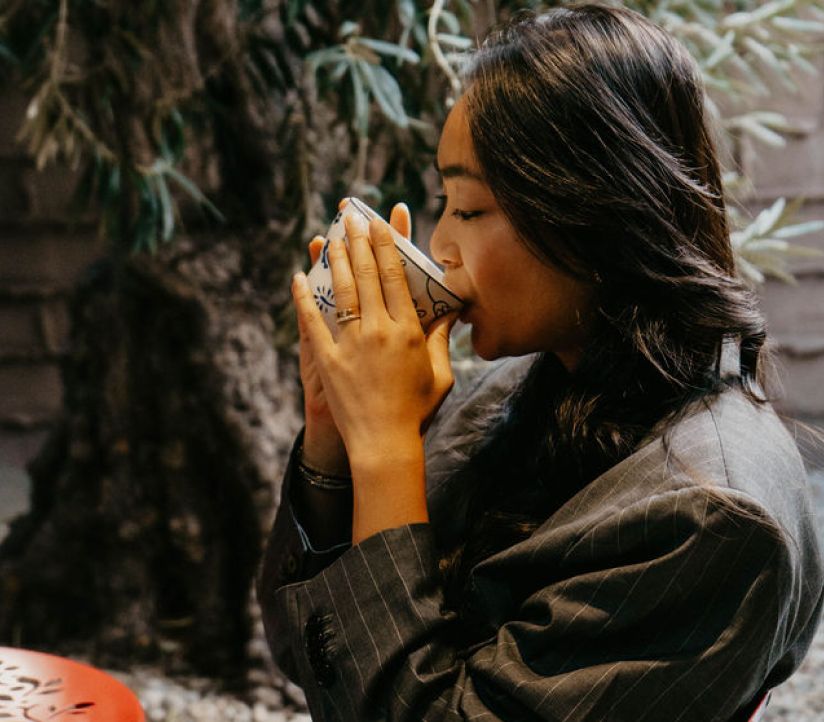 A woman sipping tea from a small porcelain cup