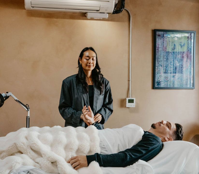 A practitioner standing beside a patient resting on a treatment table